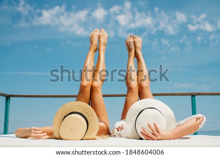A day on the beach. Two girls are lying  and raised their legs up