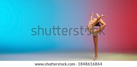 Flyer. Little caucasian girl, rhytmic gymnast training, performing isolated on gradient blue-red studio background in neon. Graceful and flexible, strong child. Concept of sport, motion, action.