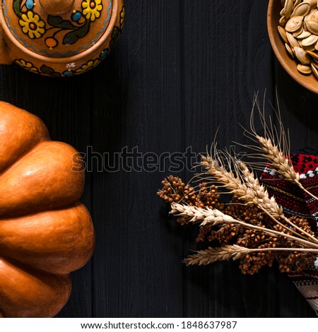 Homemade orange pumpkin and wheat ears lie on a black wood table. Autumn farm background