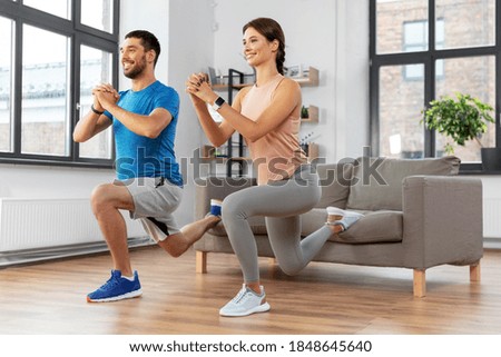 sport, fitness, lifestyle and people concept - smiling man and woman exercising and doing squats in low lunge at home Royalty-Free Stock Photo #1848645640