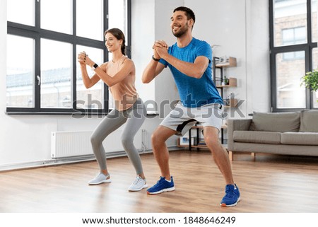 sport, fitness, lifestyle and people concept - smiling man and woman exercising and doing squats at home Royalty-Free Stock Photo #1848646249