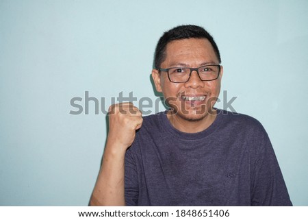 Happy and funny expression of Indonesian young man stock photo on green bright background. self potrait.