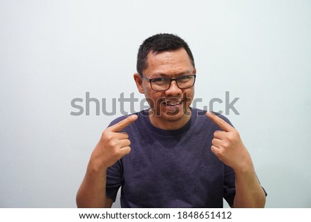 Happy and funny expression of Indonesian young man stock photo on green bright background. self potrait.