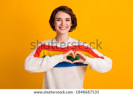 Photo of charming girl fingers show heart shape chest wear striped pullover isolated yellow color background