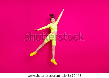 Full length body size photo of jumping high young sportswoman wearing yellow sportswear sneakers isolated on vibrant pink color background