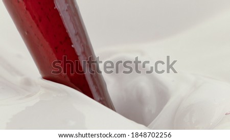 Pouring strawberry topping into milk, freeze motion. Cosmetic concept of mixing cream
