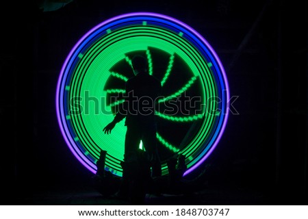 One person standing alone against a pink and blue circle light painting as the backdrop