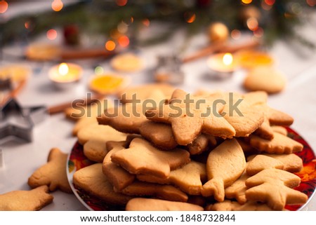 Cookies of different size and shapes in the bowl with some christmas decoration on the background