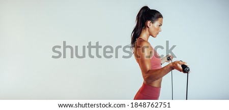 Side view of a fitness woman standing with a skipping rope. Woman in fitness wear training with a skipping rope. Royalty-Free Stock Photo #1848762751