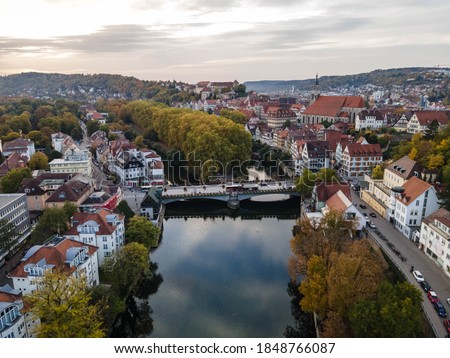 Aerial picture of city center of Tübingen, reflection of evening sky in river Neckar. Stocherkaehne and Neckarbridge in the background