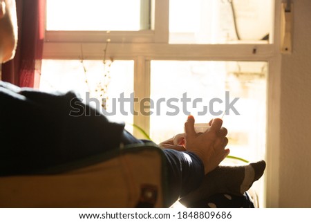 Woman drinking coffee in the backlit window