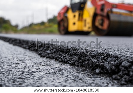 Asphalt road roller with heavy vibration roller compactor press new hot asphalt on the roadway on a road construction site. Heavy Vibration roller at asphalt pavement working. Repairing. Royalty-Free Stock Photo #1848818530