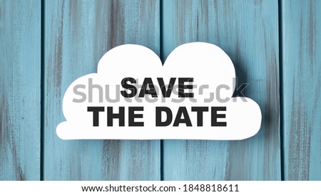 White card in cloud shape with text Save The Date on stylish wooden background