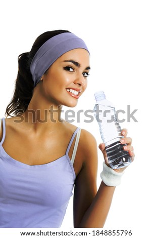 Happy smiling african american or latinos woman in sportswear drinking water, isolated over white background. Young female fitness instructor or personal trainer at studio shot. 