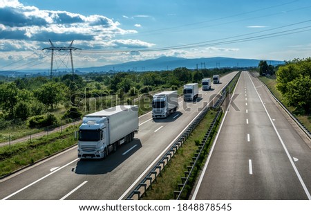 Fleet or Convoy of big transportation trucks in line  on a countryside highway under a blue sky Royalty-Free Stock Photo #1848878545