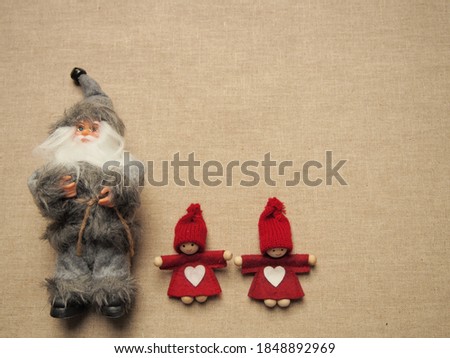 christmas card, gray santa claus with glasses and two little red elfs with white heart on dress and knitted hat on grey background, winter background wallpaper