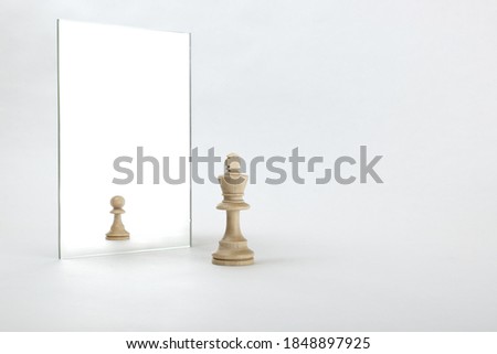 the king is reflected in the mirror as a pawn on white background. underestimation of their abilities Royalty-Free Stock Photo #1848897925