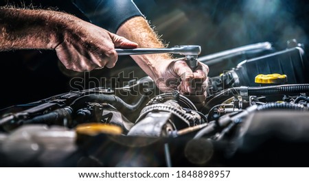 Auto mechanic working on car engine in mechanics garage. Repair service. authentic close-up shot Royalty-Free Stock Photo #1848898957