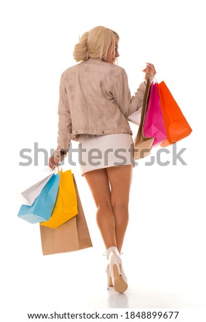 Blonde girl stands with her back to the camera and holds purchases in her hands. Beautiful girl after shopping with packages.