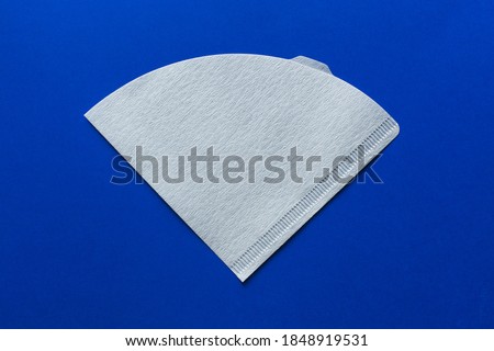 Bleached paper coffee filter isolated on a colored blue background. Alternative brewing pour over coffee. Minimalistic abstract background