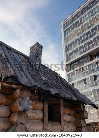 wooden hut on the background of multi-storey building