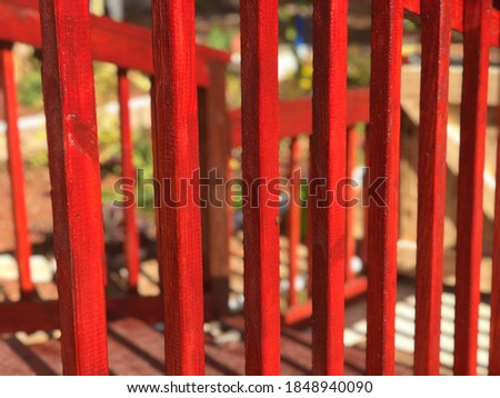 Bright beautiful red wood stain on deck rails. Picket fence concept. 