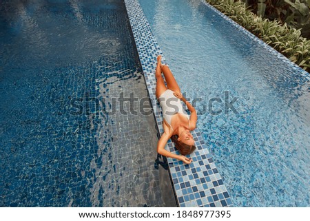 Woman relaxing in outdoor swimming pool in Bali luxury resort