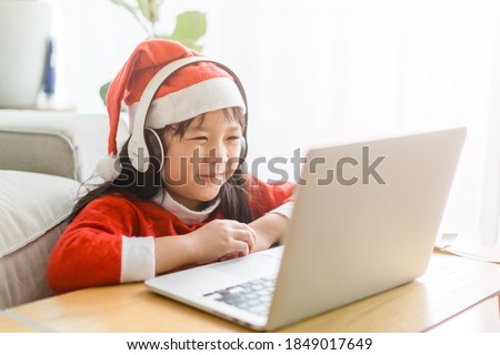 Asian girl with santa hat on christmas holidays day party.Happy girl talking video camera on laptop.Technology online with laptop at home.New normal.Covid-19 coronavirus.Social distancing.stay home.