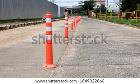 Orange traffic poles on a concrete road. Plastic poles for dividing traffic lines are lined up on the concrete road to warn you of traffic on the road with a copy area. Selective focus