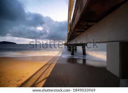 A beautiful shot of a metal pier on the beach near the ocean under cloudy sky  at Cairns Cape Tribulation Australia