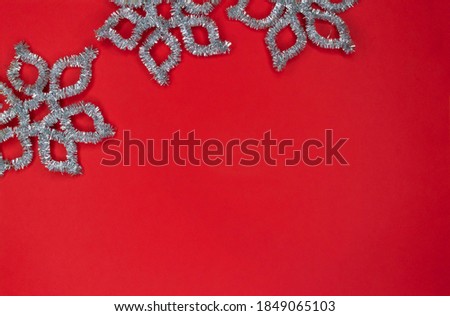 Frame made of silver snowflakes on a red background with copy space.