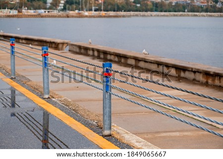 Walking and cycling path with steel rope safety barrier in the background sea Royalty-Free Stock Photo #1849065667