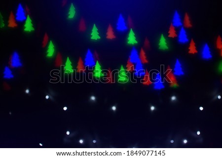 Defocused colored lights on a dark background. Colored lights in the shape of a Christmas tree.