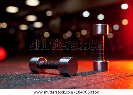Sports equipment in gym. Dumbbells on the floor. Closeup image of a fitness equipment in gym. Gym weights in warm orange light.