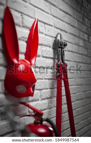 creative design of a fire brick wall with a rabbit mask, fire extinguishers and bolt cutter with a stretched chain