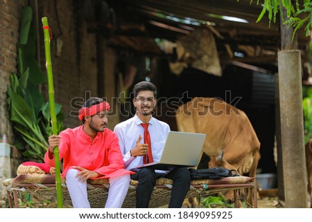 Young indian agronomist showing some information to farmer in laptop at home