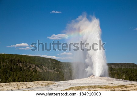 Errupting Old Faithful Geyser in Yellowstone National Park with rainbow. Royalty-Free Stock Photo #184910000