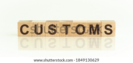 Wooden Blocks with the text: CUSTOMS. The text is written in black letters and is reflected in the mirror surface of the table. startup concept.