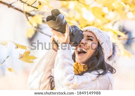 Happy photographer in a winter cap photoshoots outdoors in colorful fall nature.