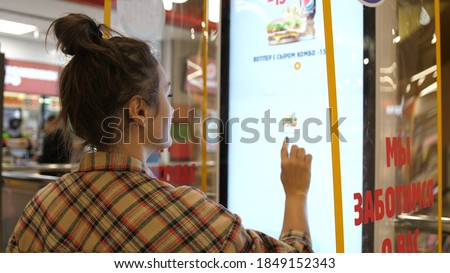 Woman types on fastfood restaurant interactive order board