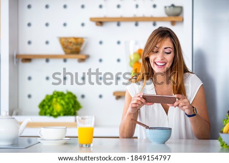 Portrait of a young food blogger, photographing the content for her blog / vlog. Food blogger photographing food. Young woman wearing casual clothes taking picture of her healthy lunch