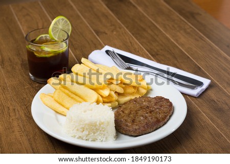 Tasty combination of hamburger with rice and fries. A refreshing glass of cola soda with lemons to accompany. Fries.