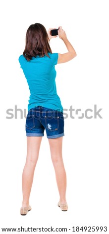 young woman in shorts photographed something compact camera. Isolated over white background. 