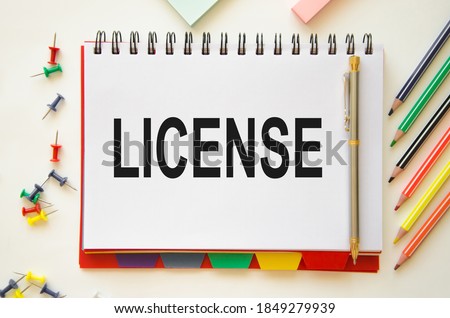 the word license is written on a notepad and deed background with pencils. the concept of giving a person the right to use anything. High quality photo