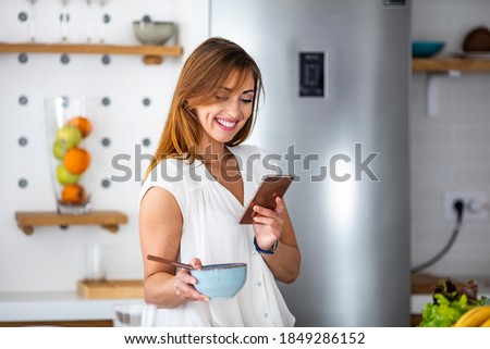 Shot of a beautiful young woman using a mobile phone in the morning at home. Those memes that make you laugh for days. Young woman drinking first morning coffee 