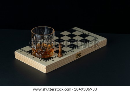 Golden brown whiskey in a glass on a dark background. Chess game and a drink. Royalty-Free Stock Photo #1849306933