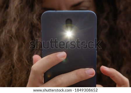 A young woman takes a photograph with a smart mobile phone, Spain.