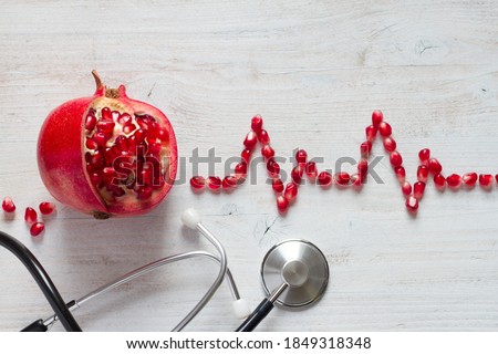 Fruit pomegranate, stethoscope and ECG cardiogram from pomegranate seeds, healthy heart diet concept abstract Royalty-Free Stock Photo #1849318348