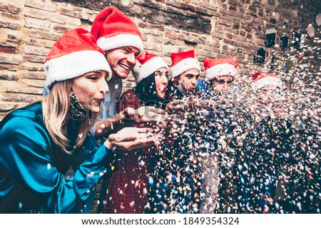 Group of happy friends with face mask celebrate all together blowing confetti and having fun in covid-19 time - Concept about happiness and joyful new year eve and party event for group of people