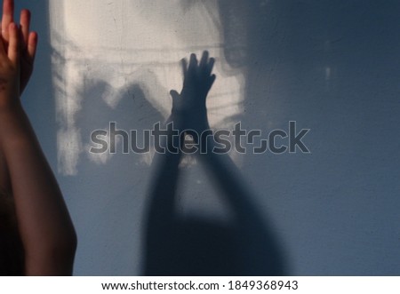 Blurry shadows of child hands on grungy wall background with copy space. Game with light and shadow